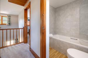 a bathroom with a bath tub and a toilet at Acorn House in Briston +33 photos