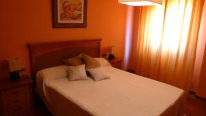 um quarto com uma cama com lençóis brancos e almofadas em Casa Rural La Guapeta em Ademuz