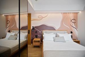 two beds in a room with a wall mural at Hotel Potami in Himare +86 photos