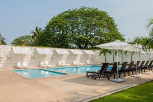 a swimming pool with lounge chairs and an umbrella at Holiday Inn Acapulco La Isla by IHG in Acapulco
