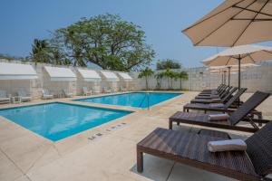 a swimming pool with lounge chairs and an umbrella at Holiday Inn Acapulco La Isla by IHG in Acapulco