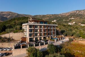 a hotel on a hill with cars parked in a parking lot at Hotel Potami in Himare