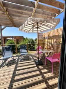 a patio with a table and chairs and an umbrella at Lodges Au Cœur des Puys in Nébouzat