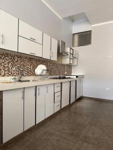 an empty kitchen with white cabinets and a sink at 4-Bedroom Apartment in Quillabamba