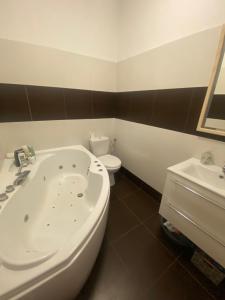 a bathroom with a tub and a toilet and a sink at Tündér Pension in Mogyoród