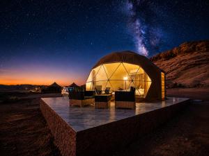 a large dome tent with chairs in the desert at night at Skylight Wadi Rum Camp in Disah +13 photos