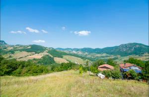 a house on a hill with mountains in the background at Stonehouse LOFT MARTA in Vergato