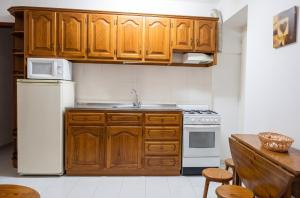 a kitchen with wooden cabinets and a white refrigerator at Charming Apartment in Alvoco da Serra - Mountain View - 50 sqm in Alvoco da Serra