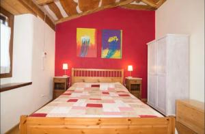a bedroom with a large bed in a red wall at Stonehouse LOFT MARTA in Vergato