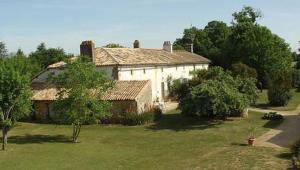 a large white house in a yard with trees at Maison charmante à Saint-Vincent-la-Châtre avec piscine partagée in Saint-Vincent-la-Châtre