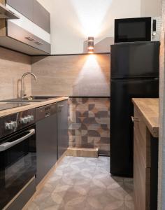 a kitchen with a black refrigerator and a sink at Appartement charmant à Briançon de 40 m² avec balcon in Briançon