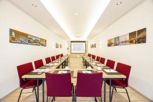 a dining room with a long table and red chairs at CityClass Hotel am Dom in Cologne