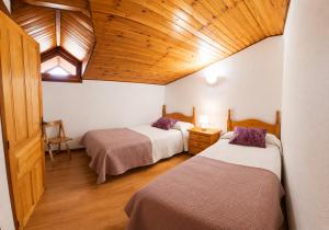 a room with two beds and a wooden ceiling at Apartamento Cholo in Brañosera +1 photo