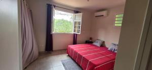 a red bed in a room with a window at Villa Tidodo in Les Anses-dʼArlets