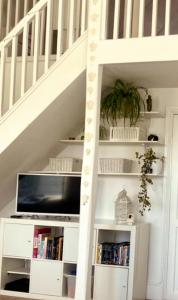 a white book shelf under a staircase with a tv at Serenity Heights in Westgate-on-Sea