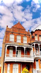 an old red brick building with a white balcony at Serenity Heights in Westgate-on-Sea