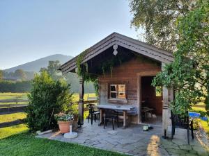 a shed with a table and chairs in a yard at Schneiderhof Ferienwohnung mit Alpenblick in Fischbachau