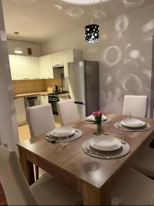 a kitchen with a wooden table with white plates and chairs at Apartament Miejski Azyl in Rybnik