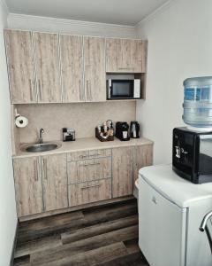 a kitchen with wooden cabinets and a sink and a microwave at Zarvantsi Hotel in Khmelëva