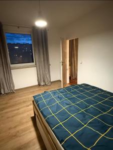 a bedroom with a blue bed and a window at Apartament Miejski Azyl in Rybnik