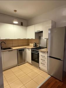 a kitchen with white cabinets and a stainless steel refrigerator at Apartament Miejski Azyl in Rybnik
