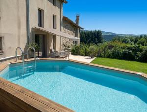 a swimming pool in front of a house at Le Nolan in Cublize