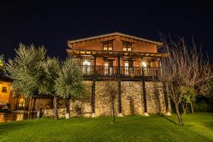 a large stone house with a deck on a lawn at Hotel Rural El Verdenal in Noceda del Bierzo