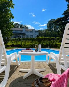 a white table and two chairs next to a pool at Hôtel au Petit Berger in La Malbaie