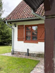 a white house with brown doors and a window at Siedlisko Mieruniszki in Mieruniszki