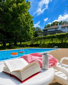 an open book sitting on a white table next to a pool at Hôtel au Petit Berger in La Malbaie +47 photos
