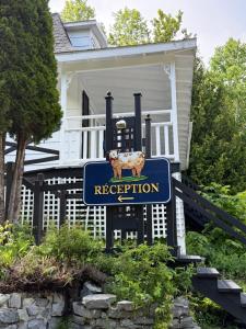 a sign with a cow on it in front of a house at Hôtel au Petit Berger in La Malbaie