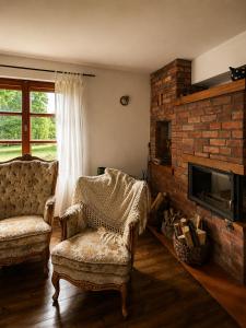 a living room with two chairs and a fireplace at Siedlisko Mieruniszki in Mieruniszki +30 photos