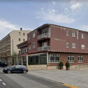 a black car parked in front of a red building at Pensión Pastoriza in Vimianzo