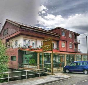 a building with a car parked in front of it at Pensión Pastoriza in Vimianzo +8 photos