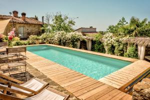 a swimming pool with a wooden deck and chairs at Antica Dimora in Capolona