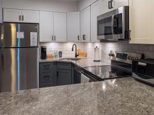 a kitchen with white cabinets and a stainless steel refrigerator at Killington resort: Walk to Mountain, Biking & Pool in Killington