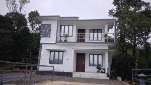 a white house with a balcony on top of it at Venus Valley Vagamon in Vagamon