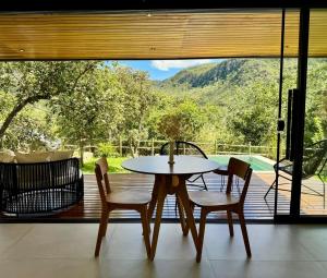 a table and chairs in front of a large window at Arandu Bangalô in Cavalcante