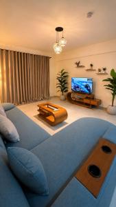 a living room with a blue couch and a flat screen tv at 1 BDR Pool Front Cozy Apartment in Port Ghalib