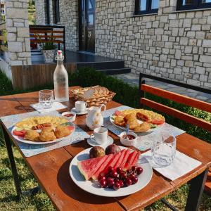a wooden table with plates of food and a bottle of wine at Villa Balliu in Berat