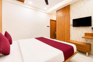 a bedroom with a white bed and a television at Hotel The Lavendra Heritage in Patna