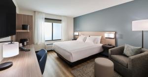 a hotel room with a bed and a chair at Hyatt Select Louisville North in Jeffersonville