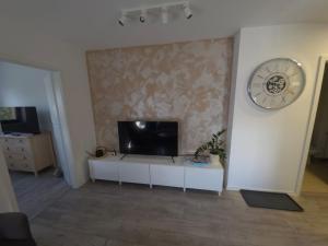 a living room with a tv and a clock on a wall at Cely's Ap Class Park in Târgovişte +10 photos
