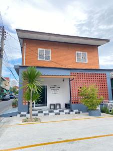 a building with a palm tree in front of it at Rose & Nainee House Hatyai in Ban Tha Thon