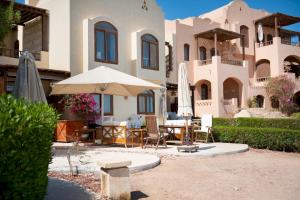 a patio with a table and umbrella in front of a house at VESTA - El Gouna Residence in Hurghada
