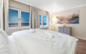 a white bed in a bedroom with windows at Lööws Roos in Wenningstedt +19 photos