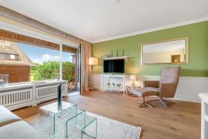 a living room with a couch and a chair and a mirror at Lööws Roos in Wenningstedt