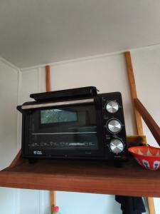 a black microwave sitting on top of a shelf at Rustika Tiny House in Pucón