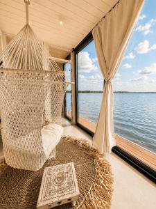 a hammock on a boat with a view of the water at Bohéa Spa Hausboot mit Sauna und Kamin in Schwielochsee