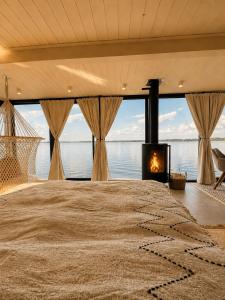 a bedroom with a large bed with a fireplace at Bohéa Spa Hausboot mit Sauna und Kamin in Schwielochsee
